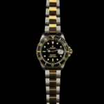 image of a 2002 Rolex Submariner 16613 two-tone watch with a black dial. The watch features a classic design with a stainless steel and yellow gold combination, showcasing a unidirectional rotating bezel and luminous hour markers. The black dial complements the gold and steel elements, creating a sleek and timeless aesthetic.