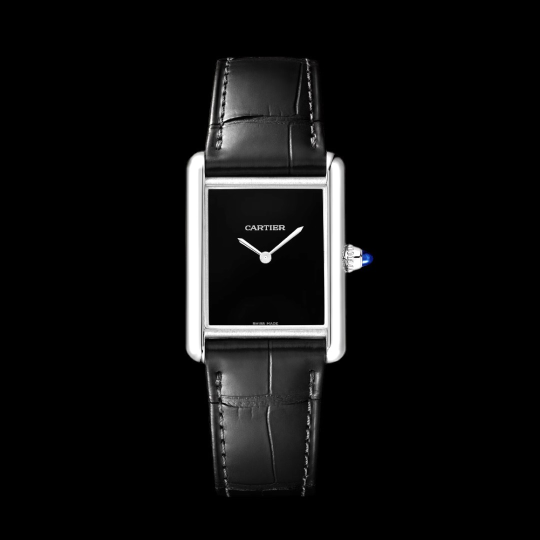 Stock photo of a Cartier Tank watch with a rectangular black lacquer dial. The watch has a sapphire crystal and an alligator strap band, with a Cartier buckle clasp. Additionally, the watch has a quartz movement and a beaded crown set with a synthetic cabochon-shaped spinel.